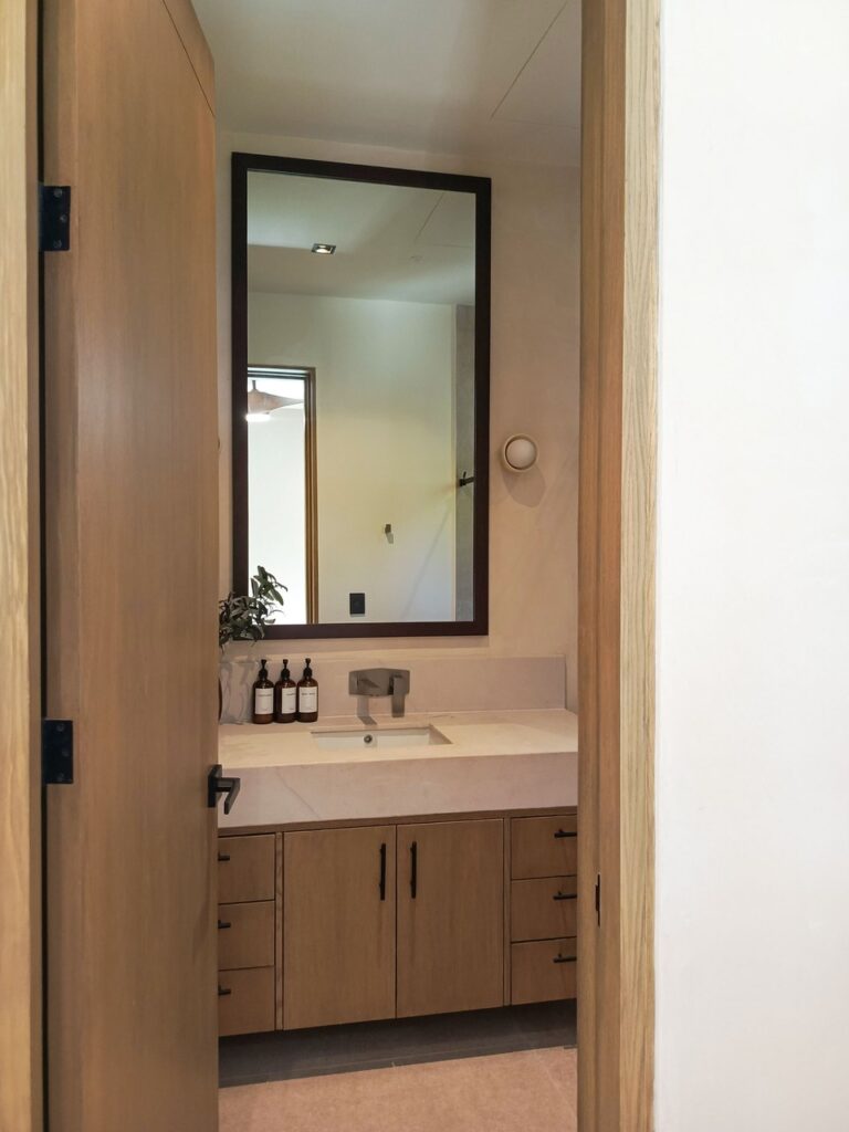 Baño con tocador de madera vista desde acceso, Casa Anexa Vida
