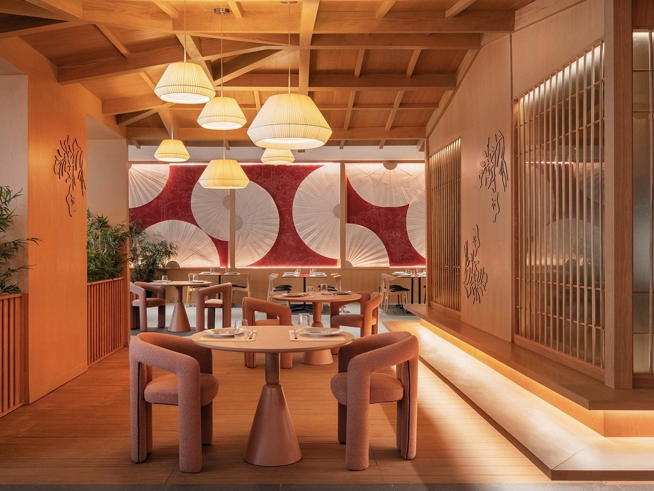 Comedor con mural textil rojo y blanco y lámparas colgantes en restaurante asiático fusión