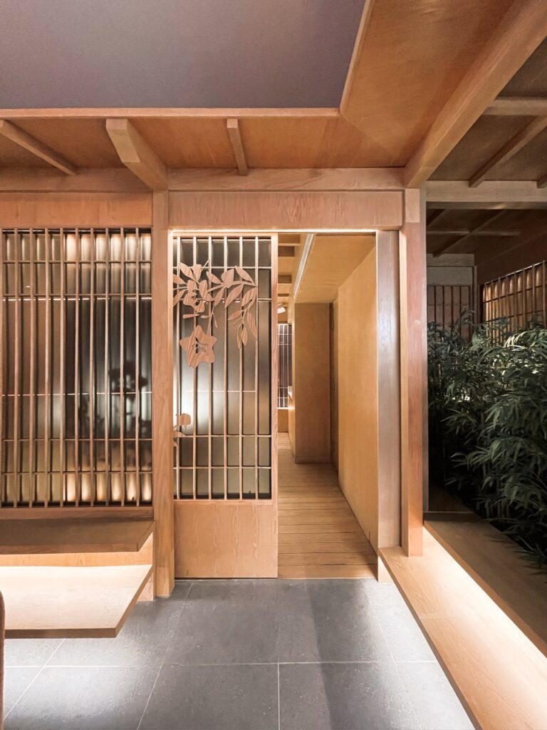 Pasillo con puerta corrediza de madera calada en restaurante japonés