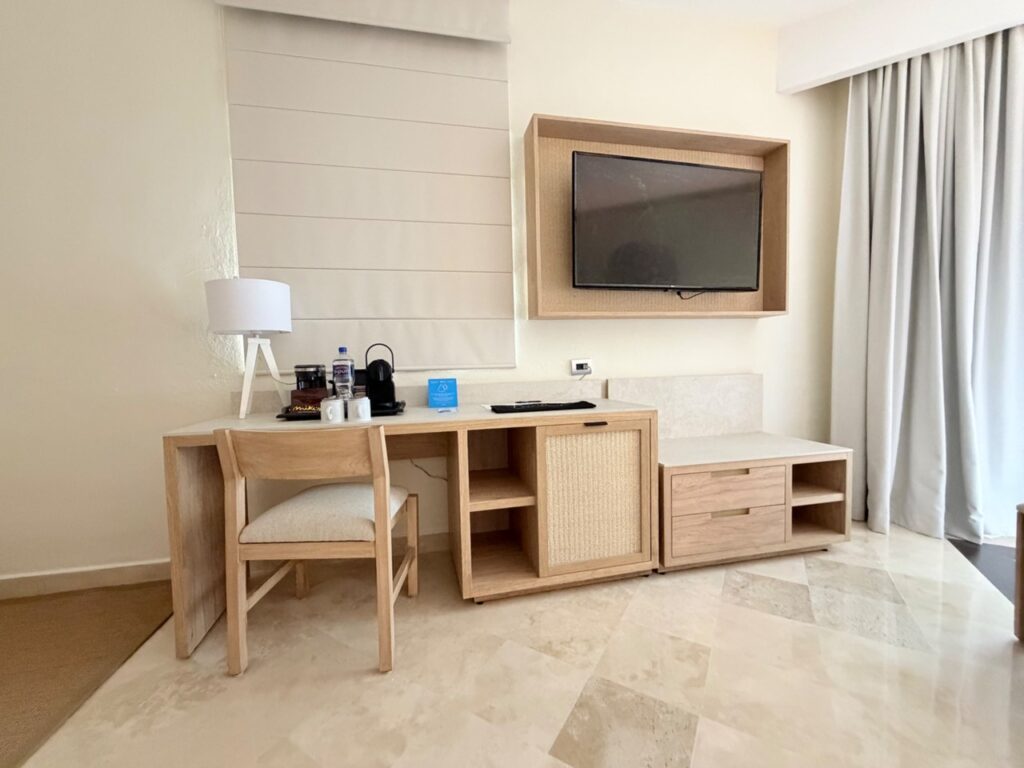 Escritorio y mueble de televisión en madera clara con puerta de rejilla en Ocean Maya Royale
