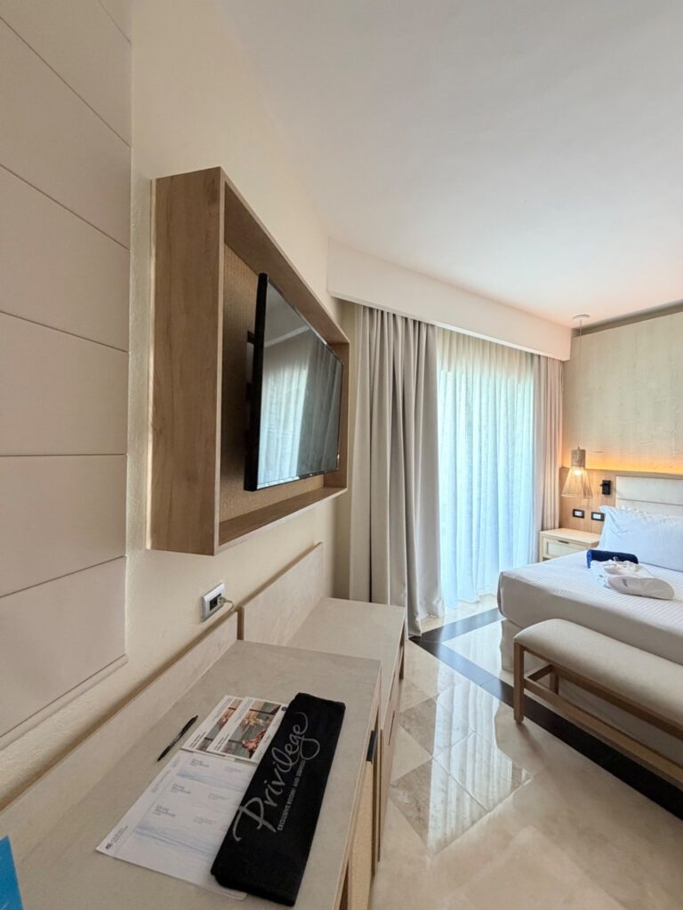 Marco de madera para televisión visto de lado, con la cama y la ventana al fondo