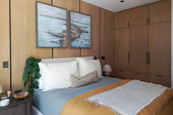 Recámara con clóset de madera y arte de paisaje marino, Casa Anexa Vida