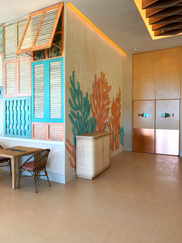 Mural de coral tallado junto a puertas con inlay de pez, Marea