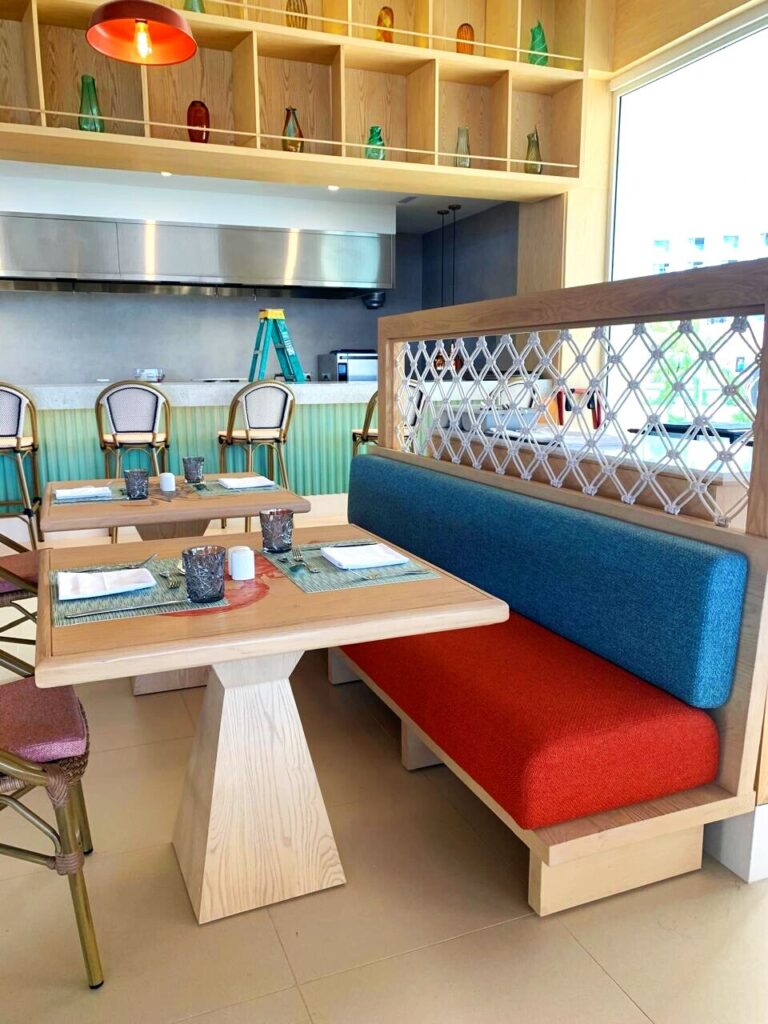 Booth con mesa montada, malla de cuerda y cojines de color, Marea